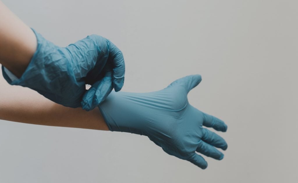 Person putting on medical gloves as demonstration of major step in the history of hand washing.