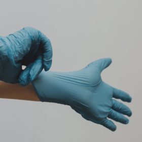 Person putting on medical gloves as demonstration of major step in the history of hand washing.