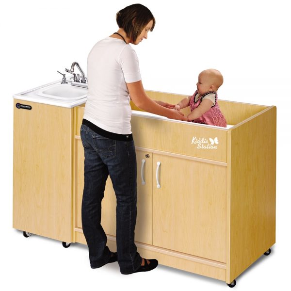 Woman and Baby Using Kiddie Station Diaper Changing and Portable Hot Water Handwashing Sink with Maple Cabinets and White Integrated ABS Countertop and Single Sink Basin